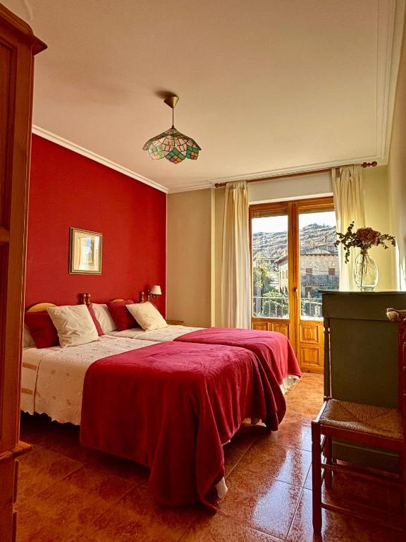 a bedroom with a large bed with a red wall at Casa Laiglesia in Uncastillo