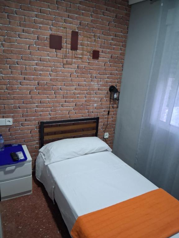 une chambre avec un lit et un mur de briques dans l'établissement Nueva 6, à Algésiras