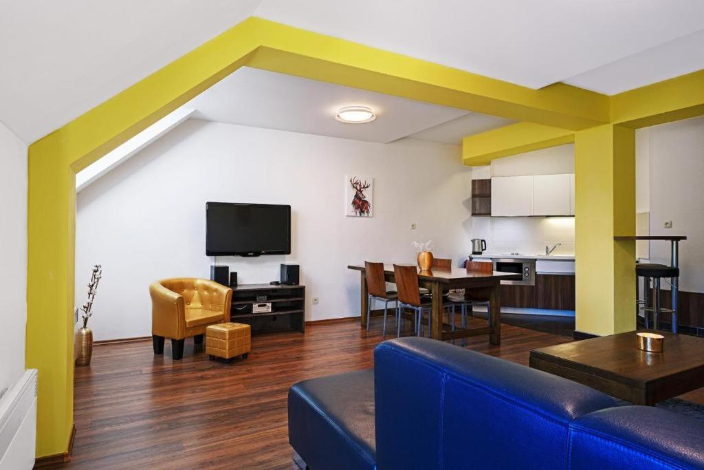 a living room with a blue couch and a kitchen at Apartmán 44 in Donovaly