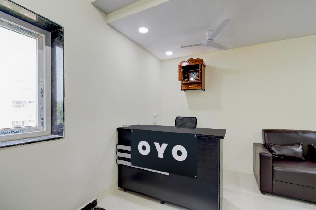 a tv in a room with a couch and a clock at SPOT ON Sriman Stay Inn in Hakīmpet