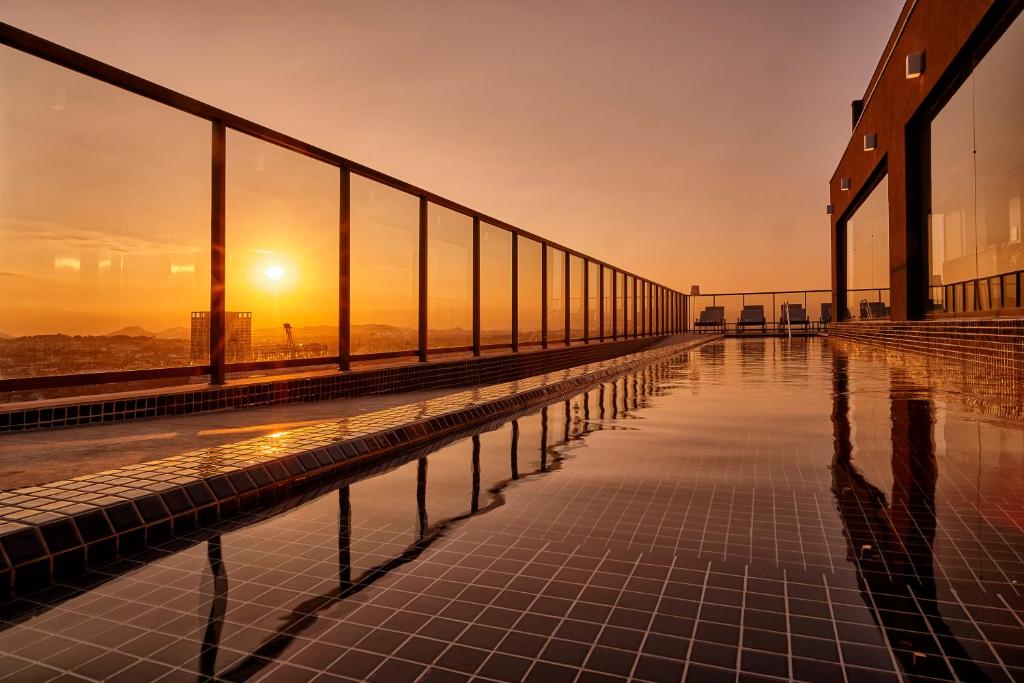 uma piscina no topo de um edifício com o pôr do sol em Intercity Rio de Janeiro Porto Maravilha no Rio de Janeiro