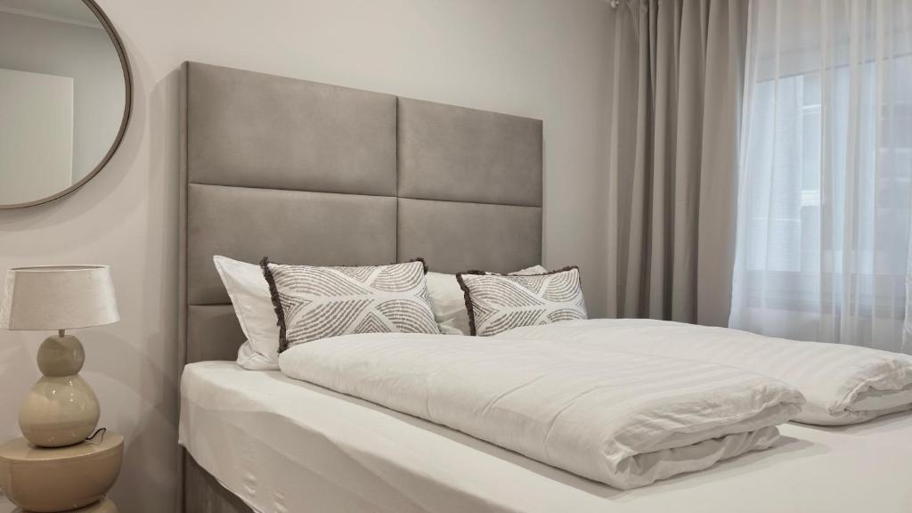 a white bedroom with a large bed with pillows at Ideale City-Wohnung mit 2 Schlafzimmern & Parking in Dortmund
