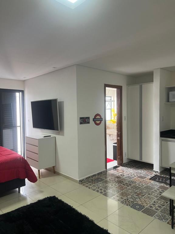 a bedroom with a bed and a tv on a wall at Flat Palladium in São Vicente