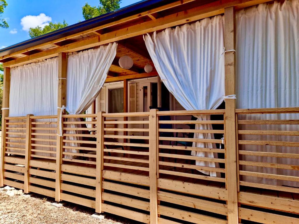 une cabane en bois avec des rideaux blancs et une clôture dans l'établissement Mobile Home Heaven Biograd, à Biograd na Moru