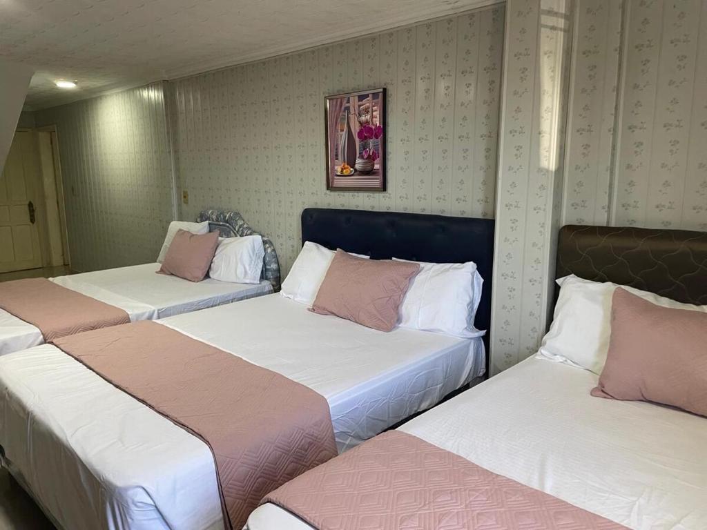 a room with three beds with pink and white at Full Encarnacion House in Encarnación