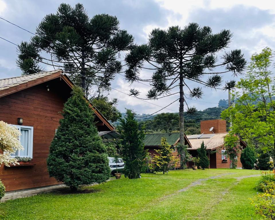 twee pijnbomen in een tuin naast een huis bij Chalé Bienz - Hospedagem Rural in Urubici