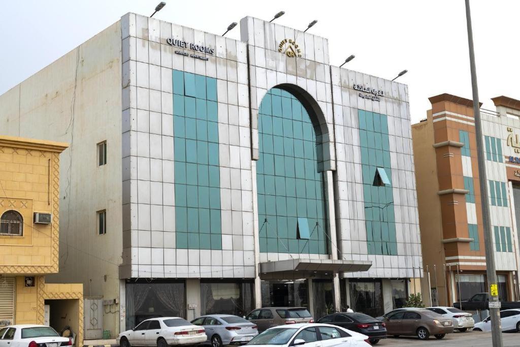 un grand bâtiment avec des voitures garées dans un parking dans l'établissement Quiet Rooms 8, à Riyad