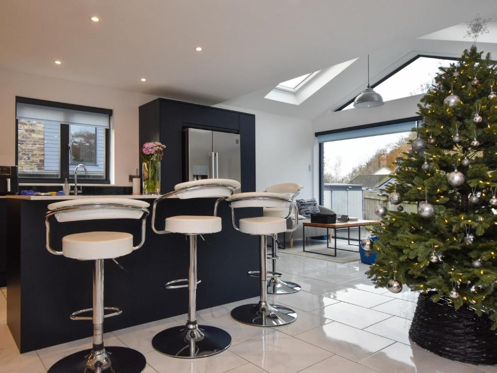 un sapin de Noël dans une pièce avec un bar et des tabourets dans l'établissement 4 Bed in Bude 89355, à Poughill