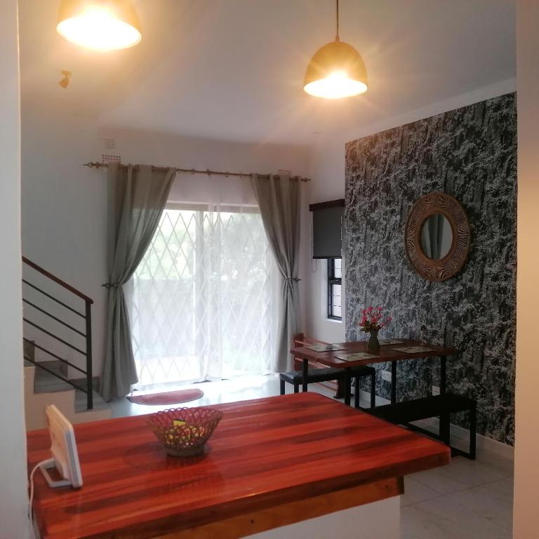 a dining room with a wooden table and a window at Villa Moni in Zomba