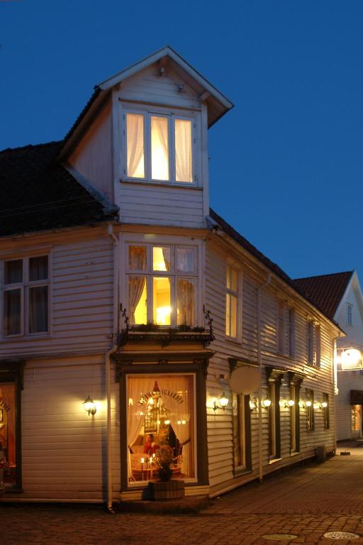 a large white house with a store window at night at Kjøbmandsgaarden Hotel in Mandal