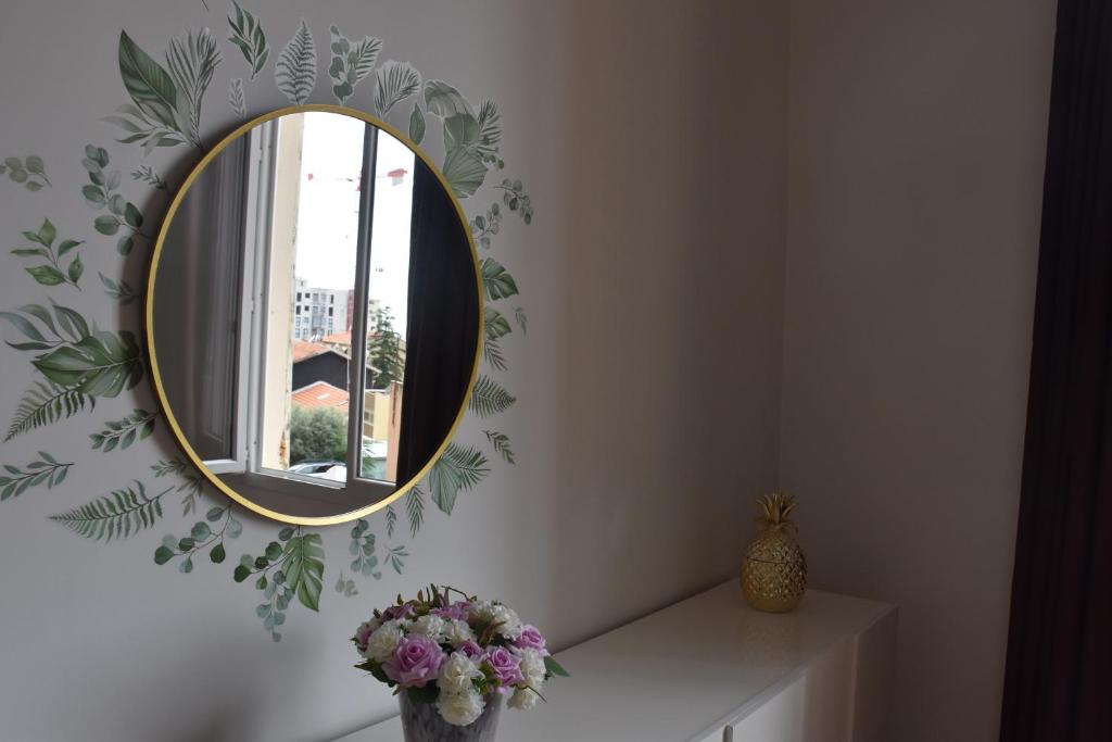 a mirror on a wall with a vase of flowers at La Maison des Trois in Beausoleil