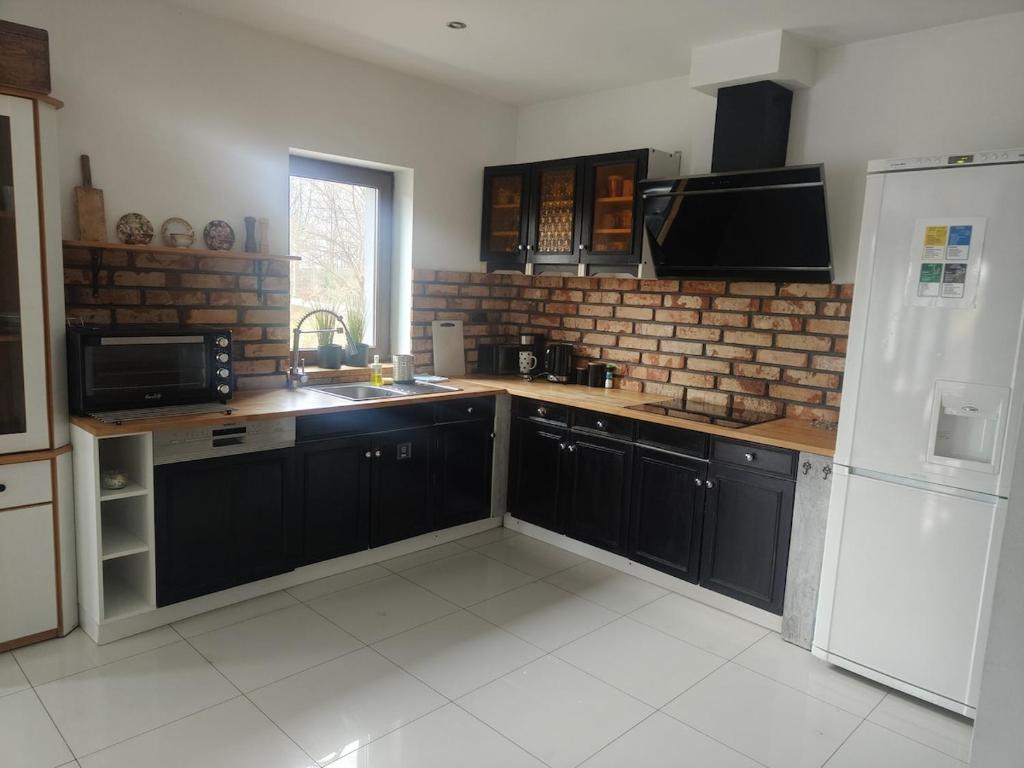 a kitchen with black cabinets and a white refrigerator at Apartament Graniczna in Bieniewice