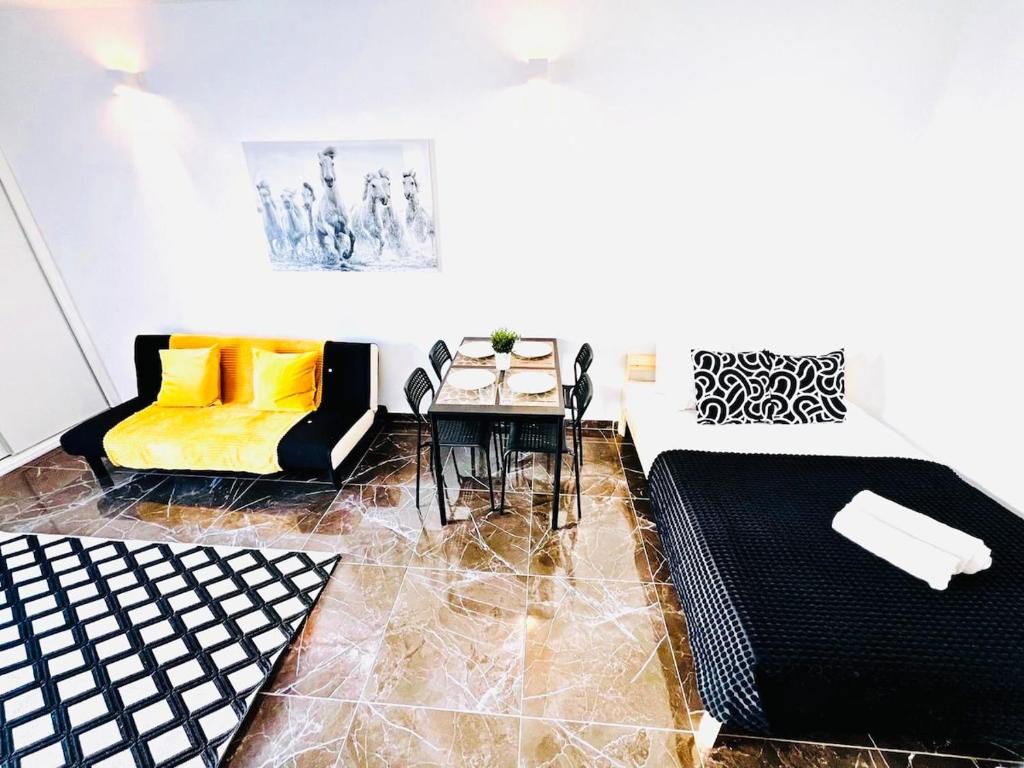 a living room with a yellow couch and a table at Studio com vista para Rua da Oura - Albufeira in Albufeira