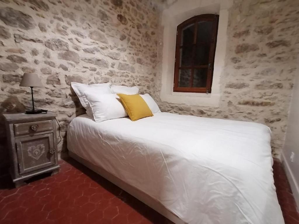 阿尔勒Extraordinaire face aux Arènes的卧室配有白色的床和石墙