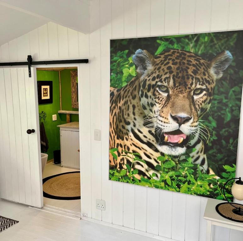a large painting of a jaguar on a wall at Piesang Valley Cottage Djungle in Plettenberg Bay