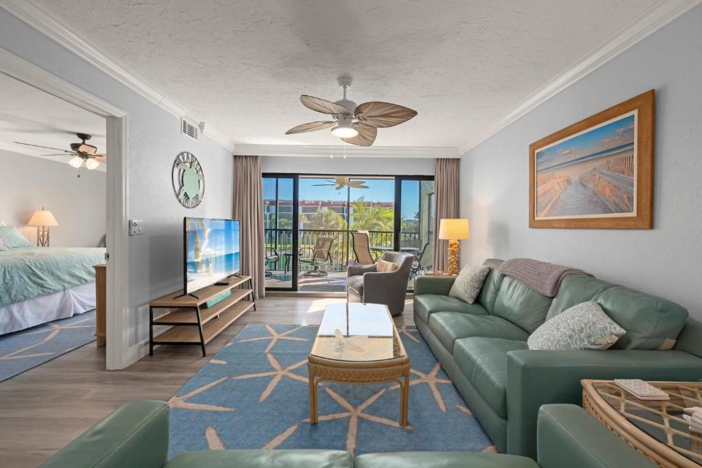 a living room with a green couch and a bed at Pointe Santo B25 in Sanibel