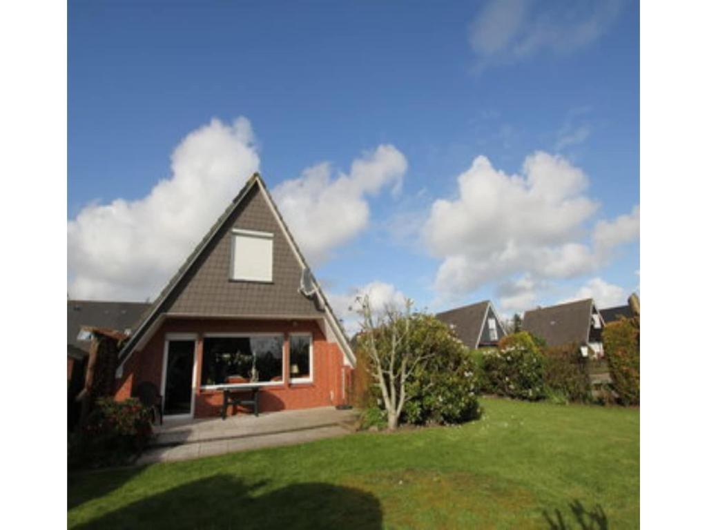 a house with a green lawn in front of it at Ferienhaus Seeschwalbe in Dornumersiel in Dornumersiel