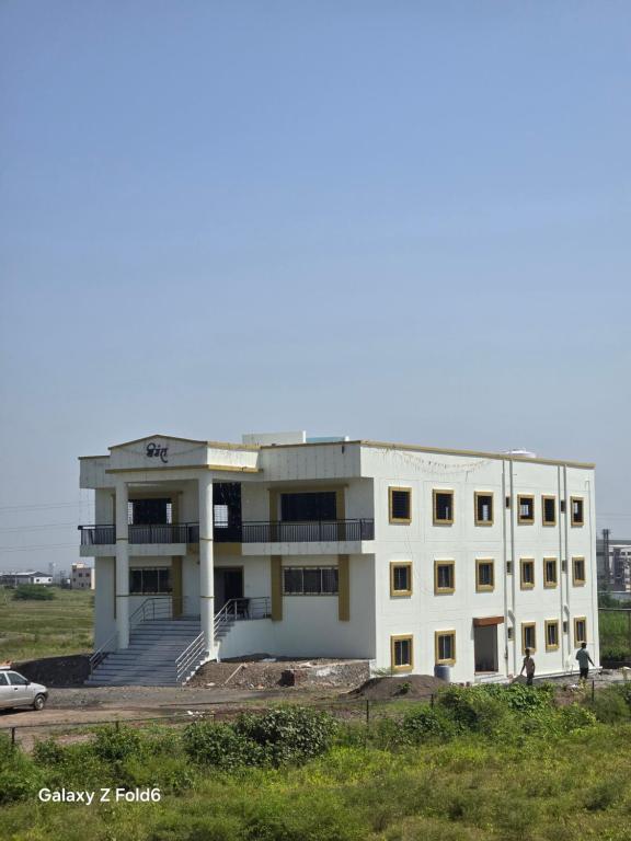 JejūriにあるShrimant Executive Lodgingの畑中白い建物