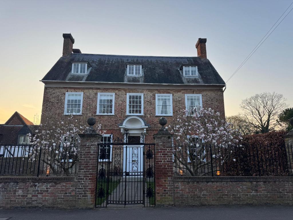 a red brick house with a black fence at The Grange, Northill in Northill