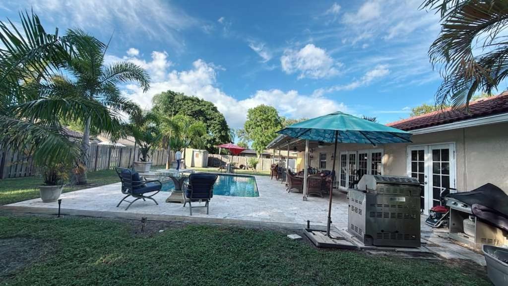 eine Terrasse mit Stühlen, einem Sonnenschirm und einem Pool in der Unterkunft Apartamento Coral springs in Coral Springs