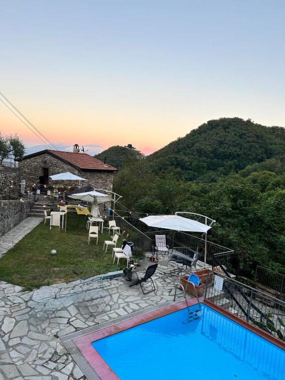 a pool with chairs and umbrellas next to a house at Casa San Bartolomeo in Riccò del Golfo di Spezia