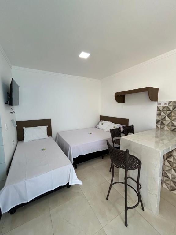 a room with two beds and a table and a chair at WT Corais Flats in Maragogi