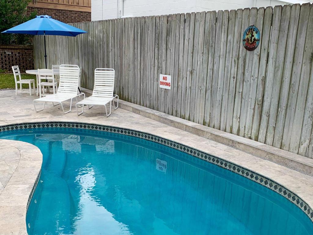 ein Swimmingpool mit Stühlen und einem Sonnenschirm neben einem Zaun in der Unterkunft Life's a Beach in Tybee Island