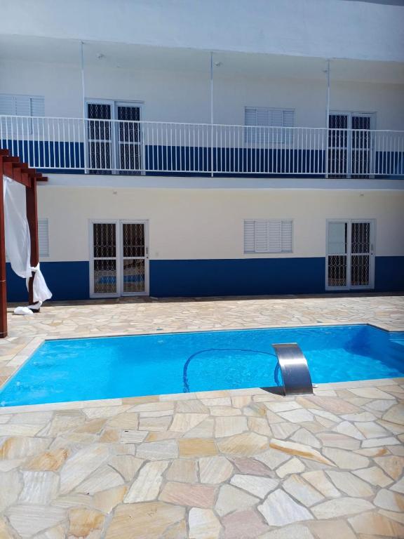 a swimming pool with blue water in front of a building at Pousada Café em Flor -Quarto Hidromassagem in Inconfidentes