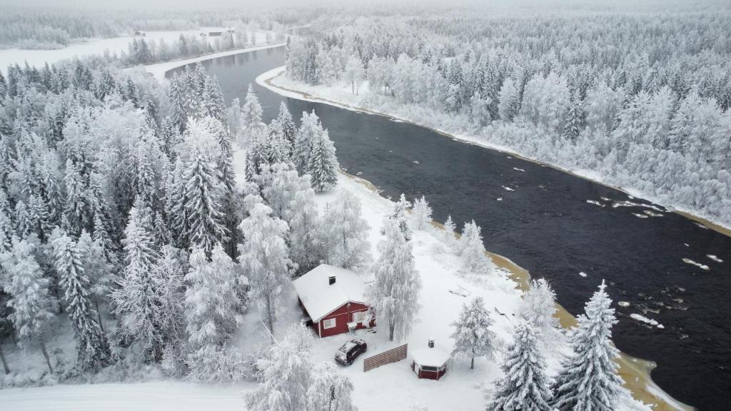 a house in the snow next to a river at Villa Jokiranta in Lapland in Ranua