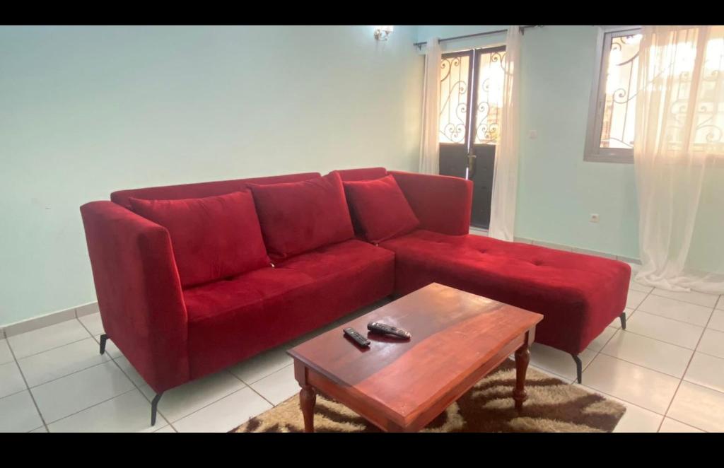 ein rotes Sofa im Wohnzimmer mit Couchtisch in der Unterkunft Les Jardins Prives Odza in Jaunde