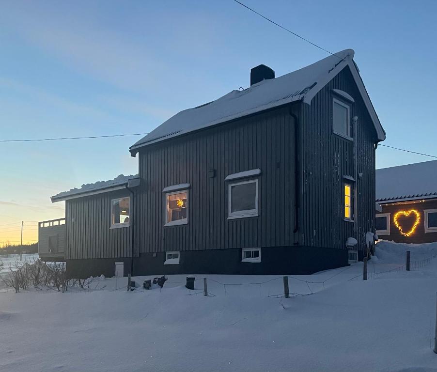 a black house sitting in the snow in the yard at Koselig hus nær sjø og fjell in Nord-Lenangen