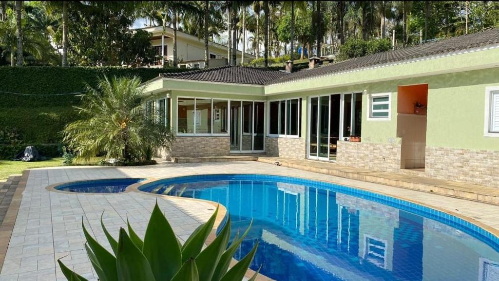 ein Swimmingpool vor einem Haus in der Unterkunft Chácara Recanto dos Lagos in Cotia