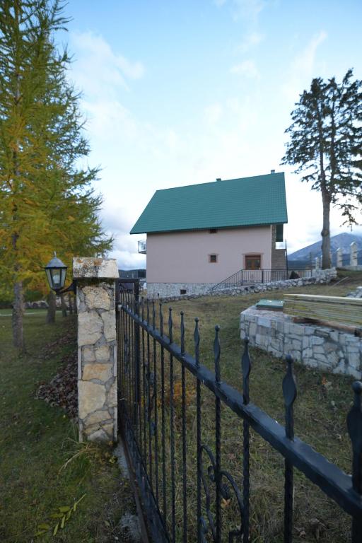 Una valla delante de un edificio blanco con techo verde. en Apartmani pod Durmitorom, 