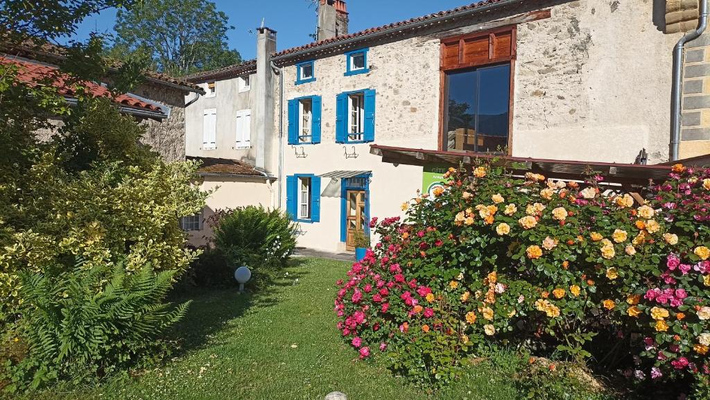 a white building with blue windows and flowers at Terra Médiane in Serres-sur-Arget