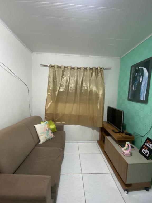 een woonkamer met een bank en een televisie bij Flat há 15 min da Pajuçara in Maceió