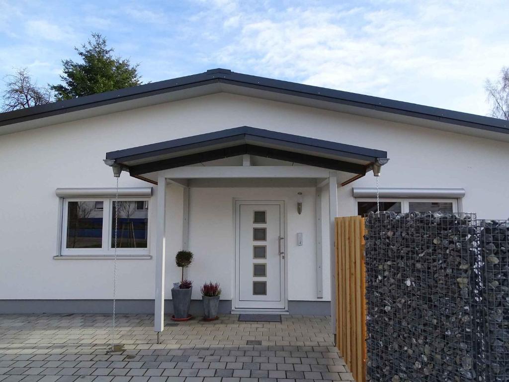 uma casa branca com um telhado preto e uma cerca em Ferienwohnung am Weinberg em Ostrach