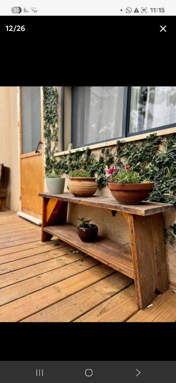 a wooden table with potted plants on top of it at מתחת לעץ התות בכפר in Bet Alfa