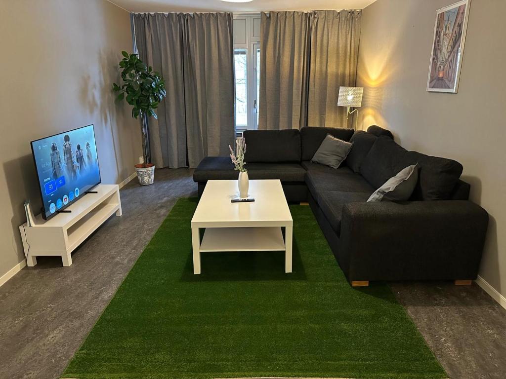 ein Wohnzimmer mit einer Couch, einem Tisch und einem Fernseher in der Unterkunft Noah Longstay Bygatan in Västerås