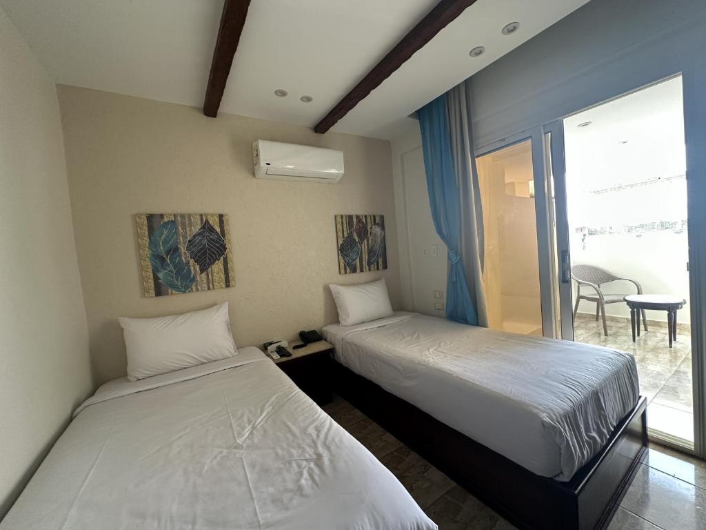 two beds in a room with a window at Giza Pyramids Inn in Cairo