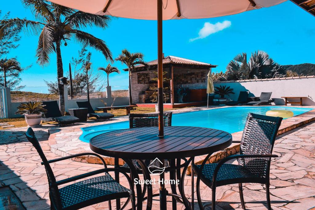 - une table avec des chaises et un parasol à côté de la piscine dans l'établissement Pousada Sweet Home, à Búzios