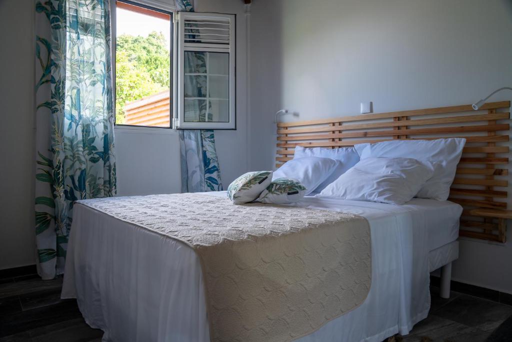 a bedroom with a bed with white sheets and a window at Casa Naya in Pointe-Noire