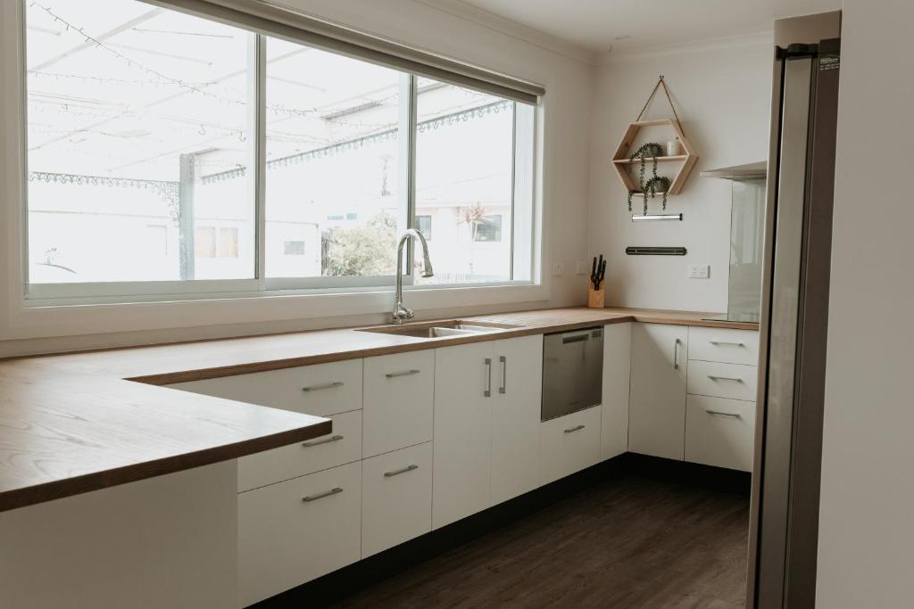 a kitchen with white cabinets and a large window at Marsden Manor - Spacious house with large pool in Greymouth