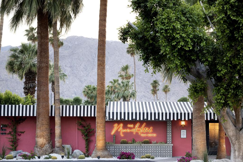 a pink building with palm trees in front of it at The Muse Hotel in Palm Springs
