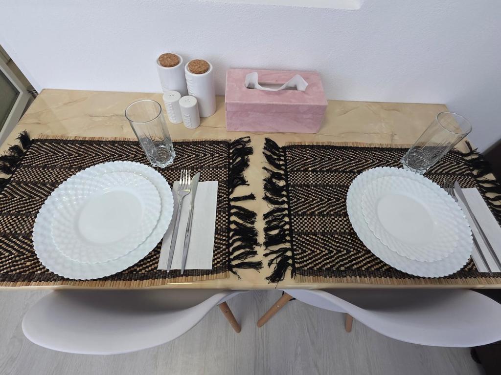 a table with two white plates on a table at Sya House in Craiova
