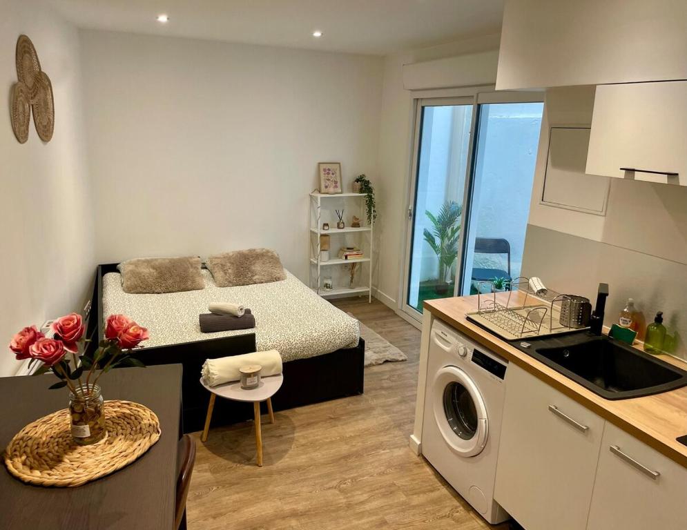 a small room with a bed and a kitchen with a washing machine at Studio cosy, proche Bordeaux et fleuve in Lormont