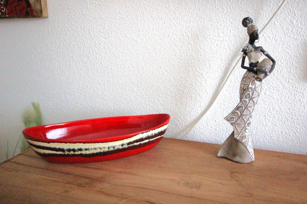 a red bowl on a wooden table with a statue at Sonja Apartman in Mogán