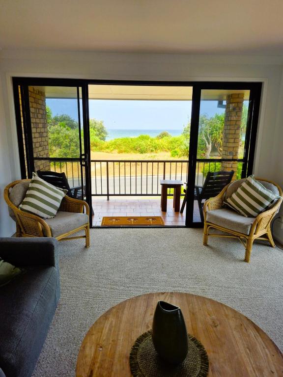 a living room with a couch and chairs and a balcony at Beachfront Bliss in Lennox Head