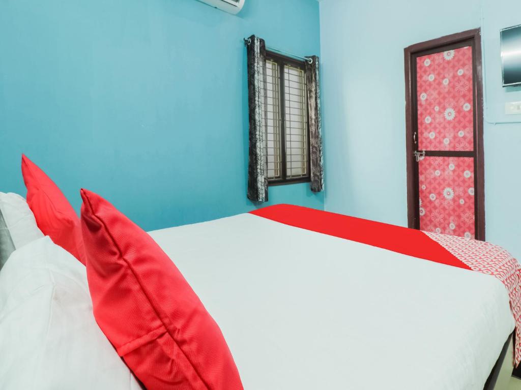 - un lit avec des oreillers rouges dans une chambre bleue dans l'établissement Hotel O Sea Coastal Inn, à Kakinada