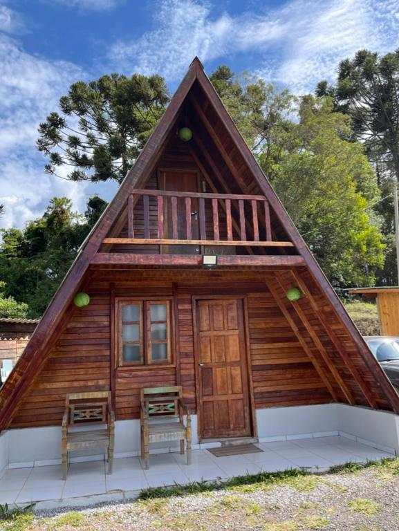a cabin with a gambrel roof and two chairs at Chalé Mirante das Estrelas in Camanducaia