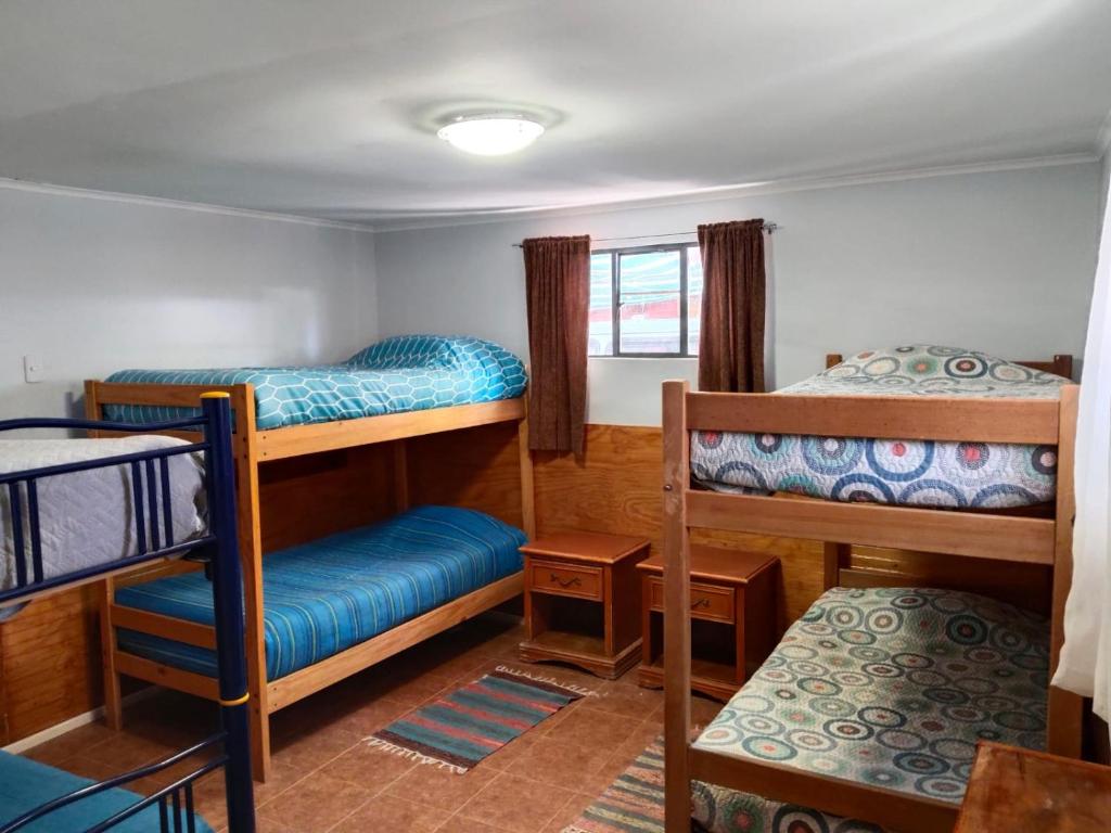 a room with three bunk beds and a window at Hostal Ribera de Quitor in San Pedro de Atacama